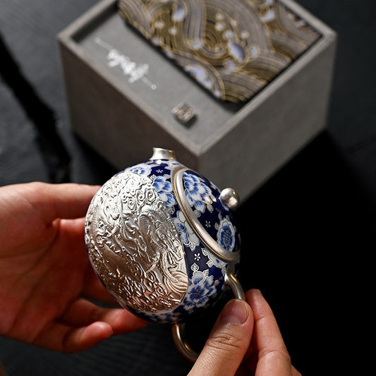 Handcrafted silver "Xishi" style teapot featuring dragon and phoenix relief, blue-and-white accents, and silver gilding; a premium Gongfu tea vessel for home use.