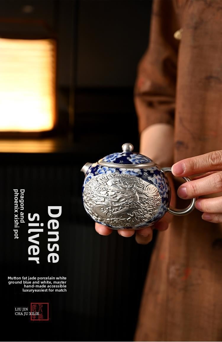 Handcrafted silver "Xishi" style teapot featuring dragon and phoenix relief, blue-and-white accents, and silver gilding; a premium Gongfu tea vessel for home use.