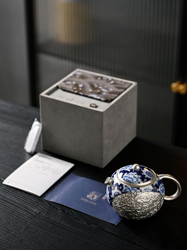 Handcrafted silver "Xishi" style teapot featuring dragon and phoenix relief, blue-and-white accents, and silver gilding; a premium Gongfu tea vessel for home use.