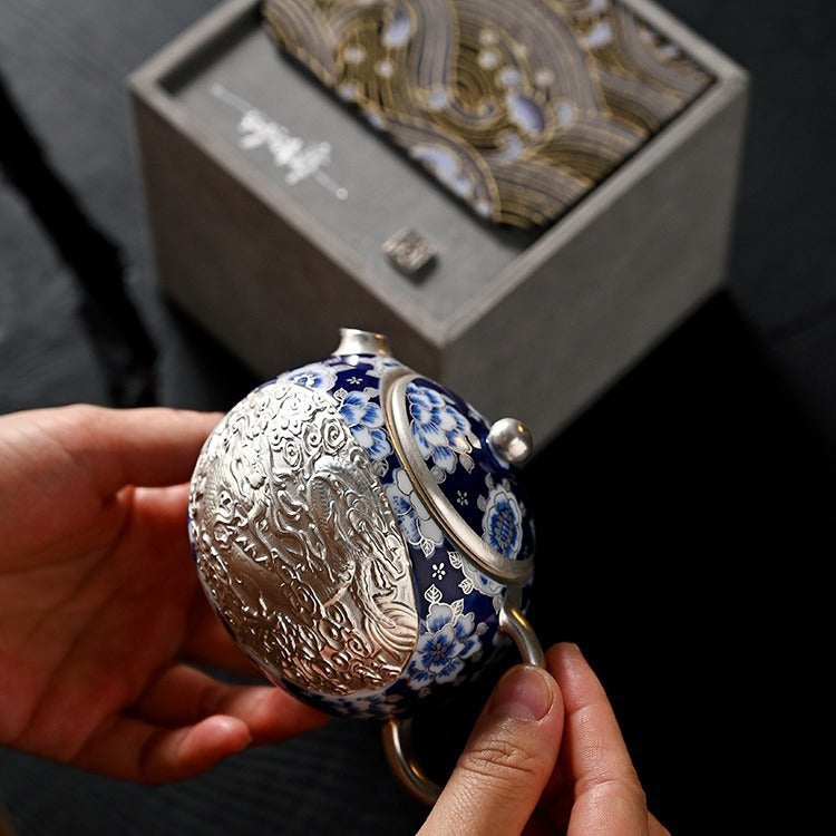Handcrafted silver "Xishi" style teapot featuring dragon and phoenix relief, blue-and-white accents, and silver gilding; a premium Gongfu tea vessel for home use.