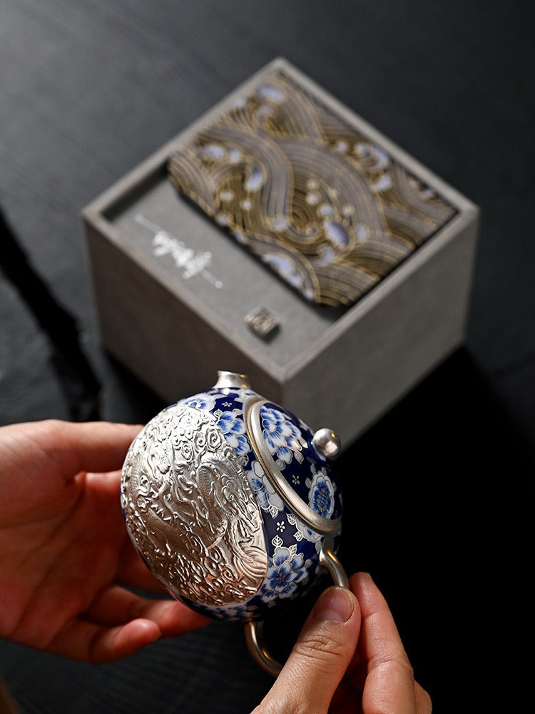 Handcrafted silver "Xishi" style teapot featuring dragon and phoenix relief, blue-and-white accents, and silver gilding; a premium Gongfu tea vessel for home use.