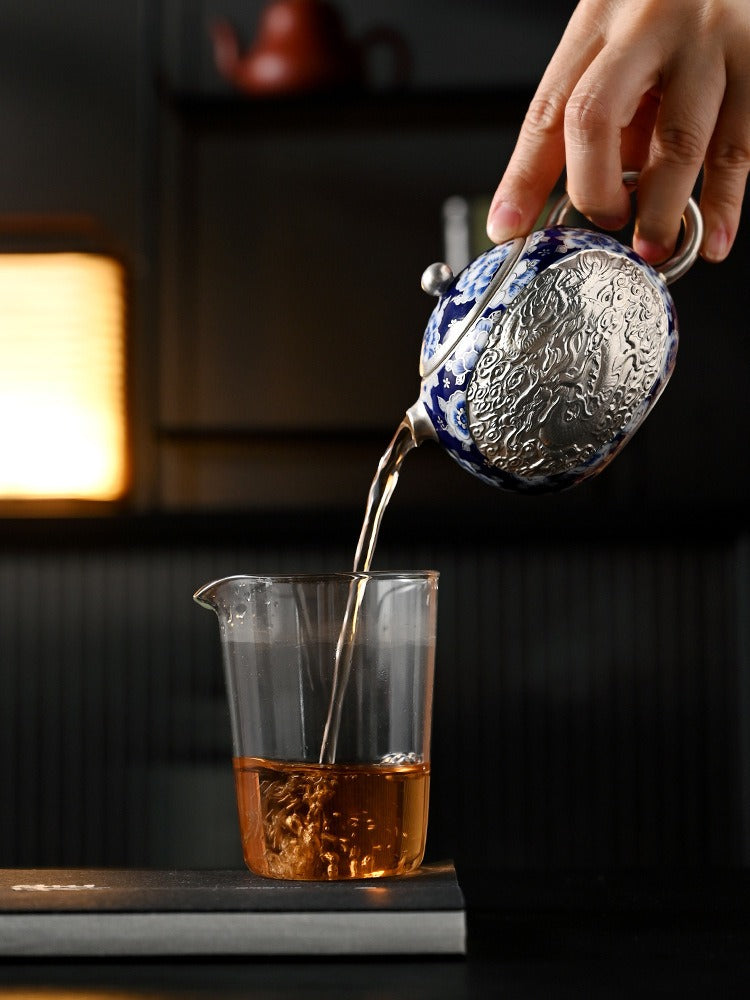 Handcrafted silver "Xishi" style teapot featuring dragon and phoenix relief, blue-and-white accents, and silver gilding; a premium Gongfu tea vessel for home use.